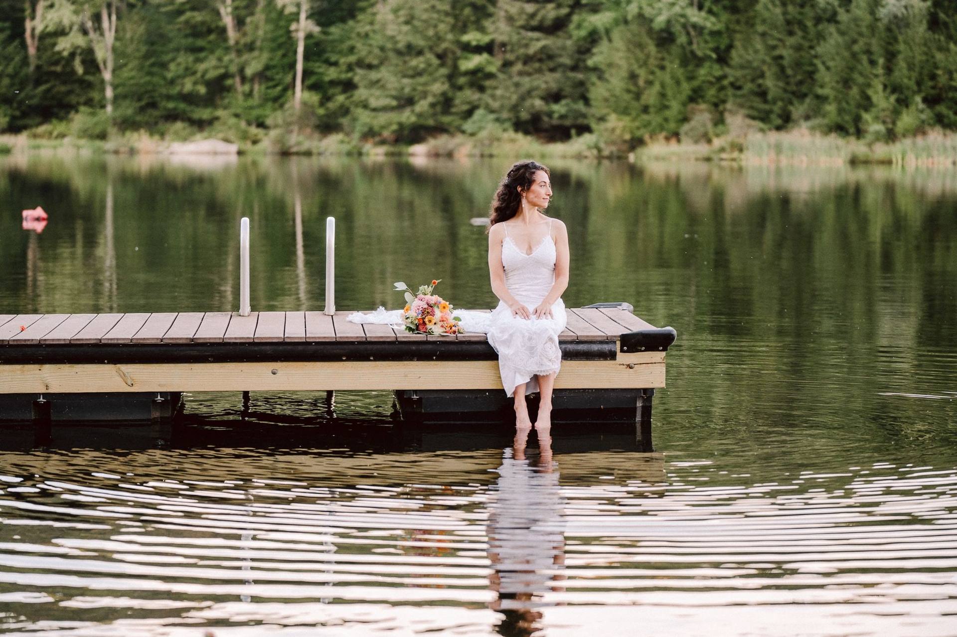 Bride seated on the dock, feet in the lake