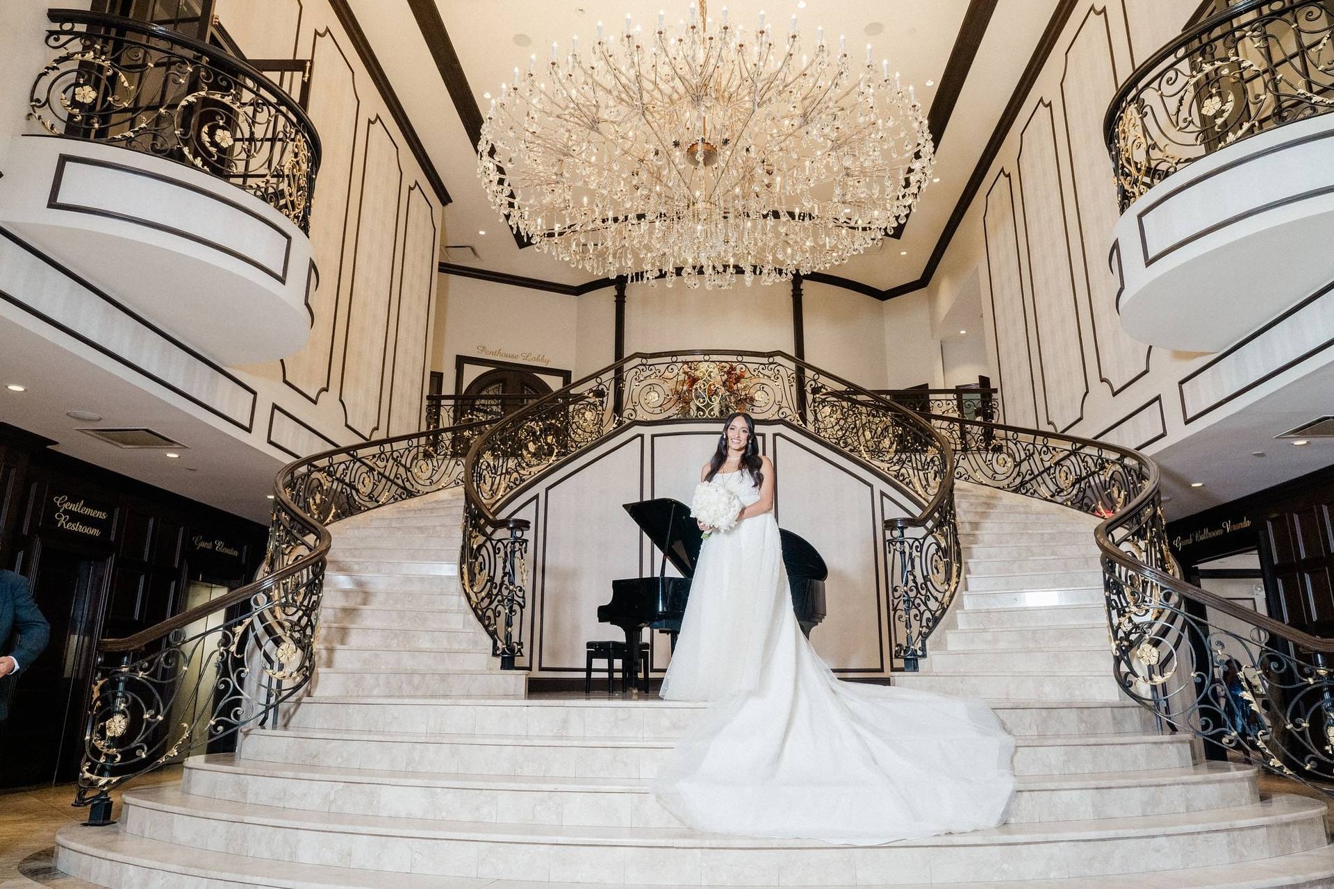 Bride on the grand staircase beneath a chandelier
