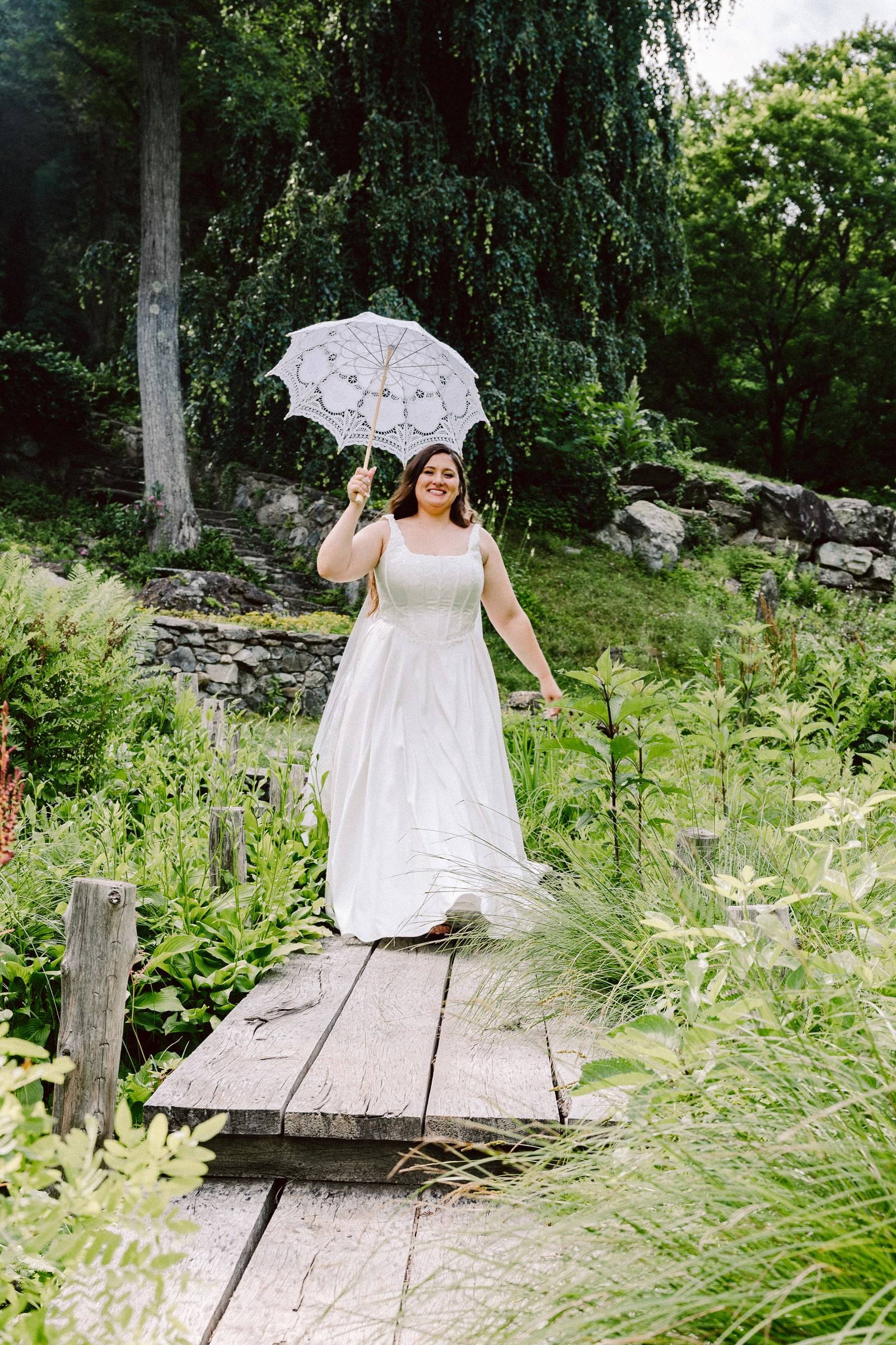 Bride with lace parasol on a garden footbridge