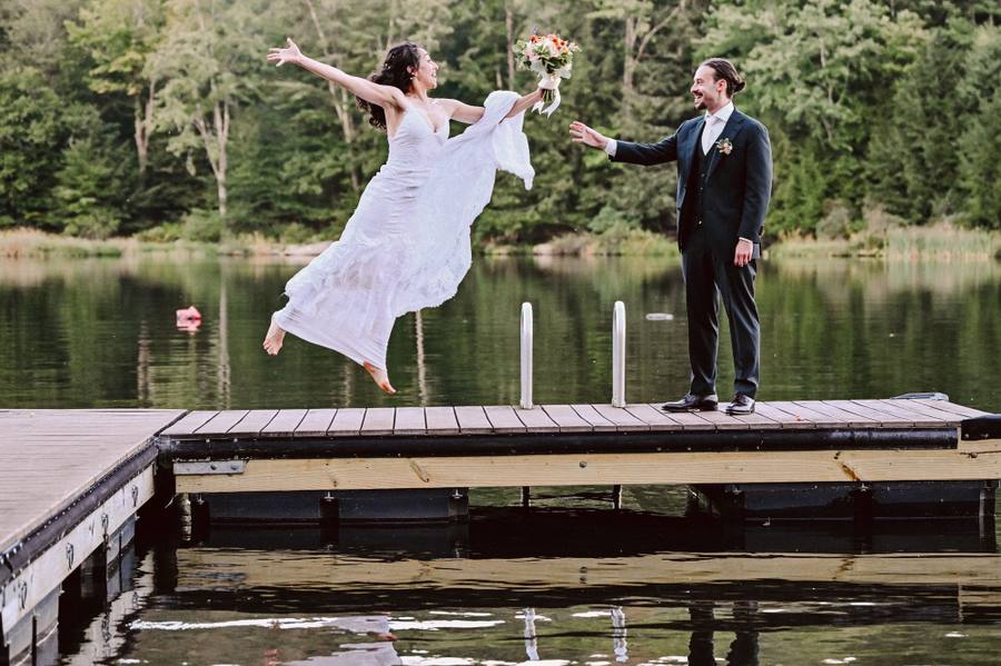 Bride mid-leap on the lake dock
