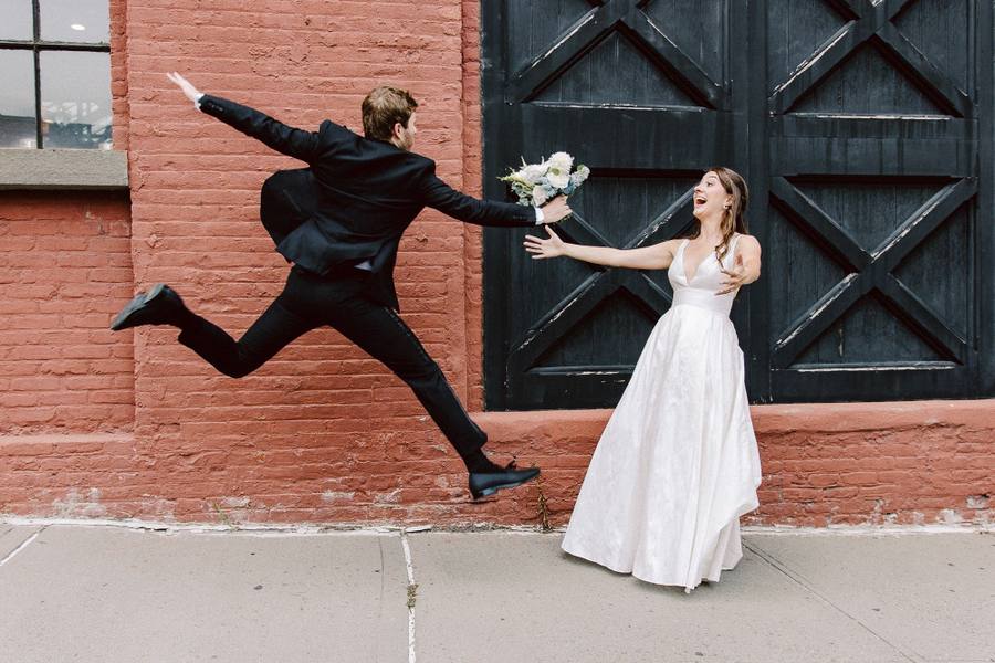 Groom leaping mid-air as the bride laughs
