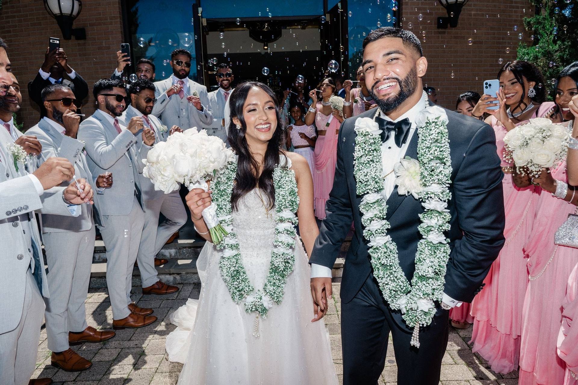 Garlanded couple cheered by the wedding party
