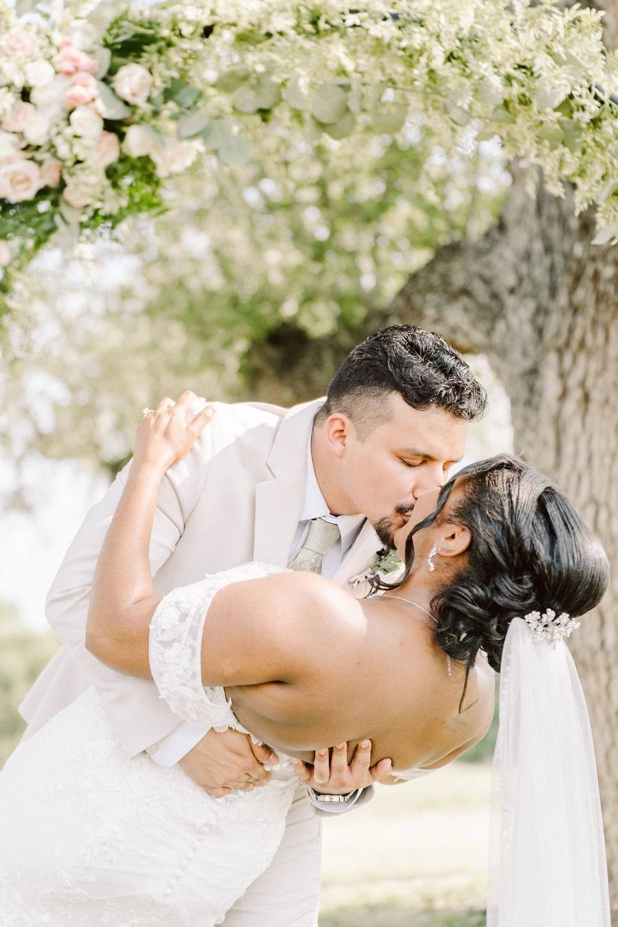 Dip kiss beneath a floral arch
