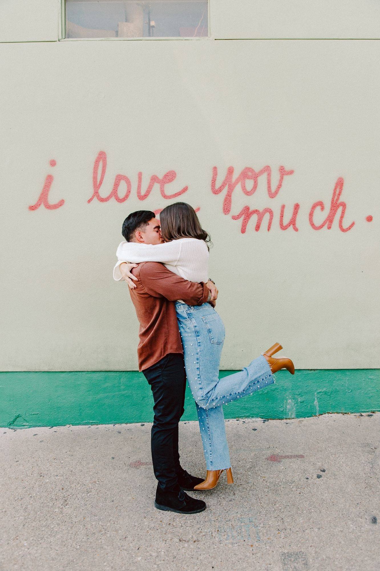Engagement lift in front of an 'i love you much' mural