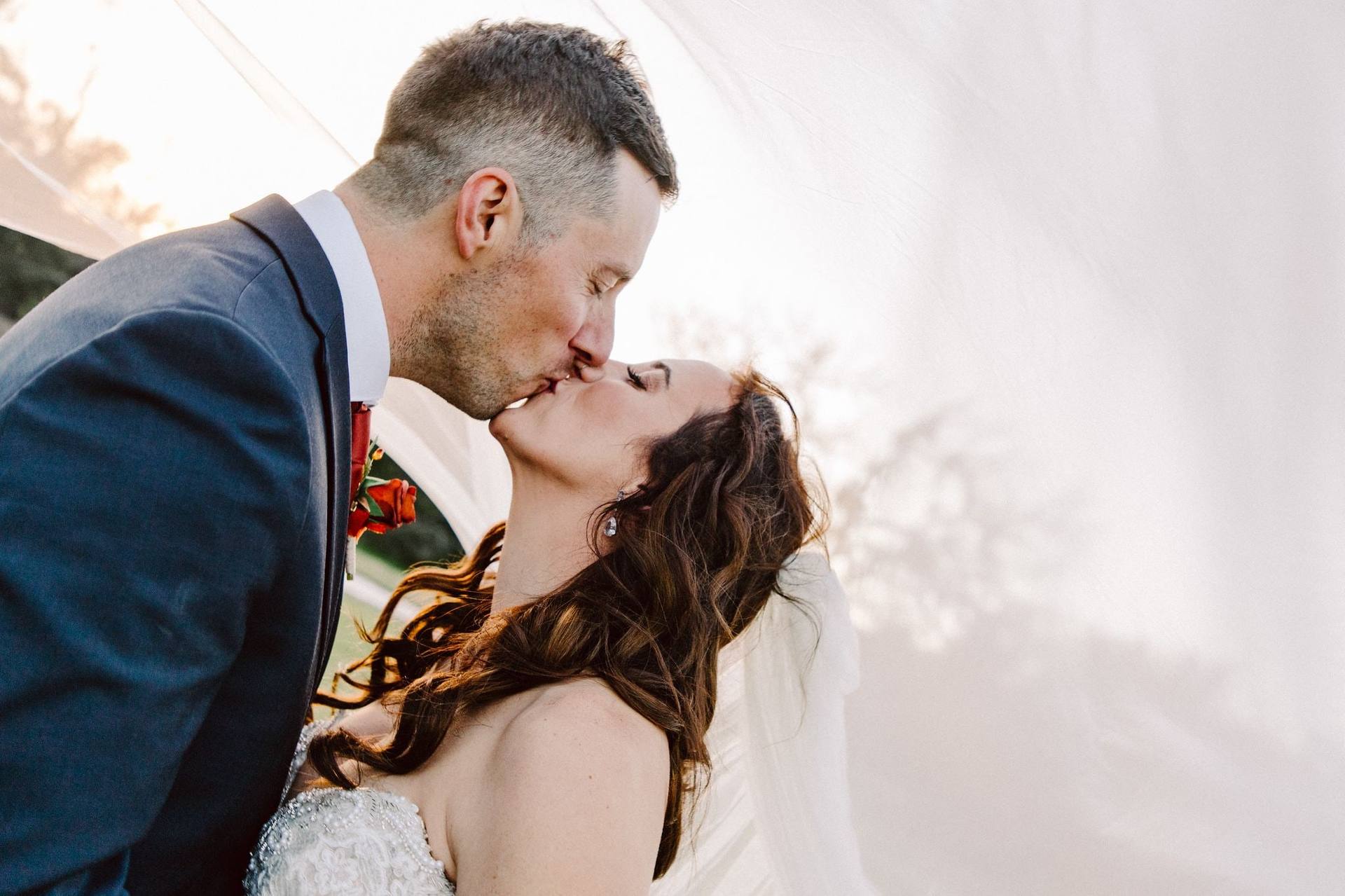 Veil-wrapped kiss in soft light