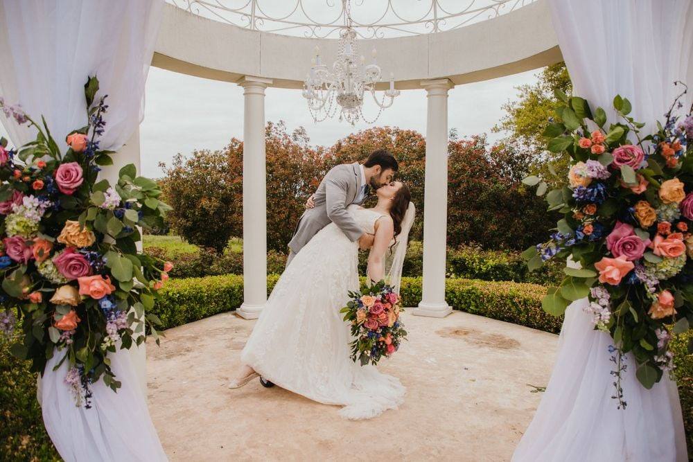 Kiss in a gazebo framed by vivid florals