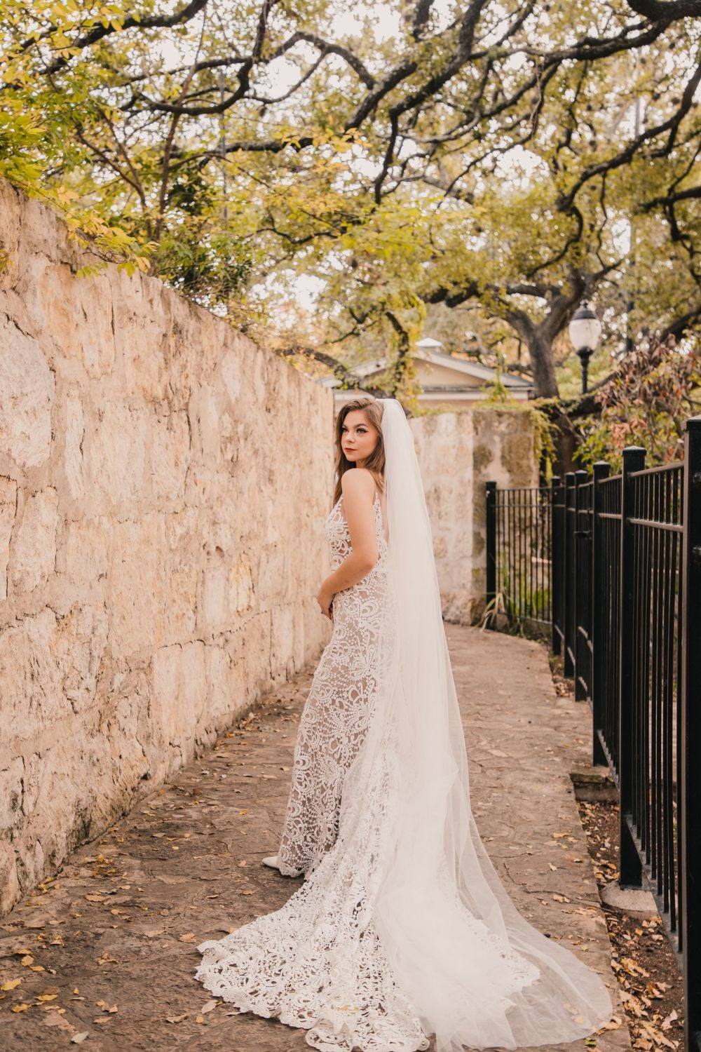 Bride with lace train on a stone garden path
