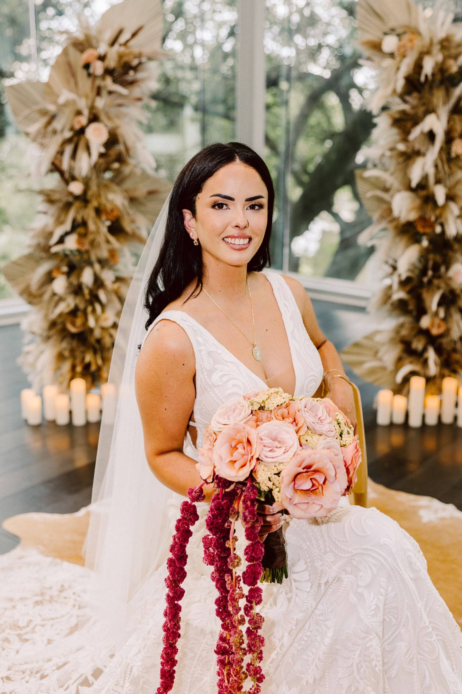 Bride with cascading bouquet seated before pampas grass