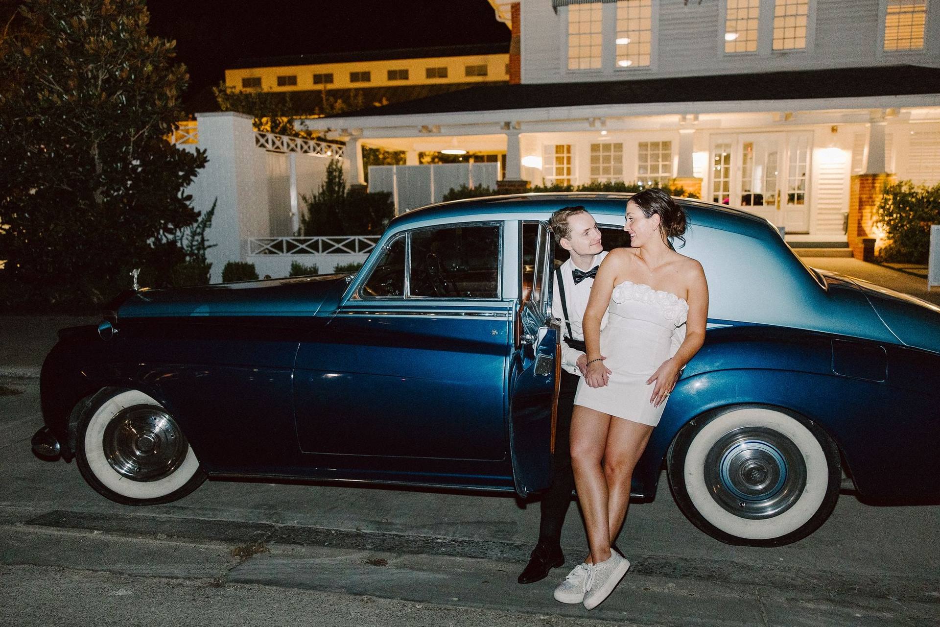 Newlyweds with a vintage car at night