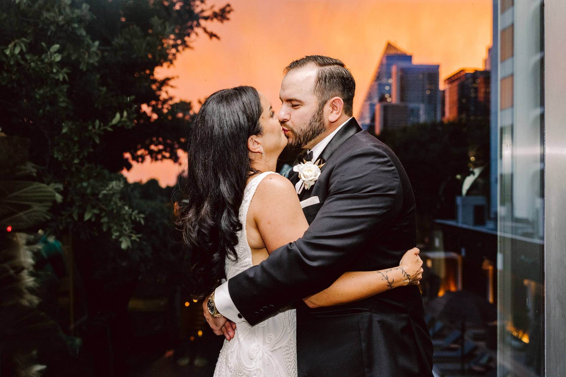 Couple kissing at sunset with the city skyline behind