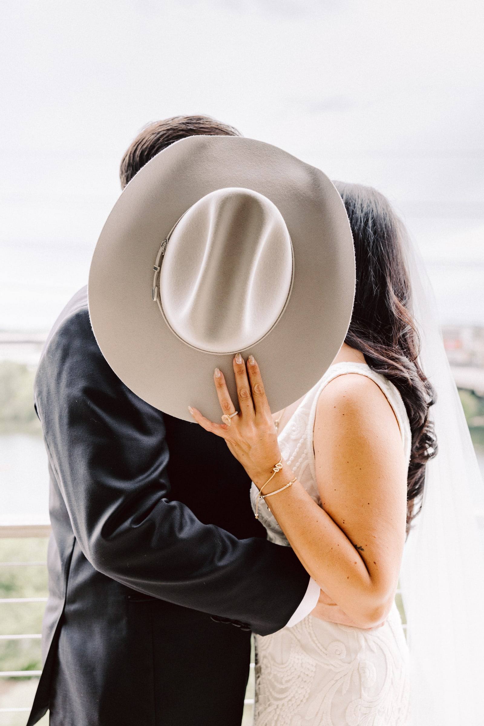 Groom hiding a kiss behind a cowboy hat