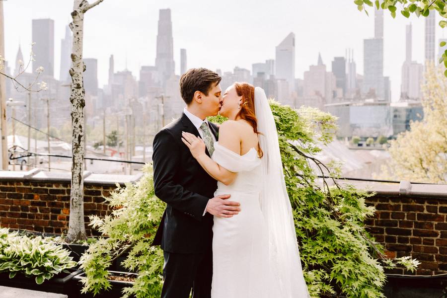 Golden rooftop kiss framed by greenery and the Manhattan skyline