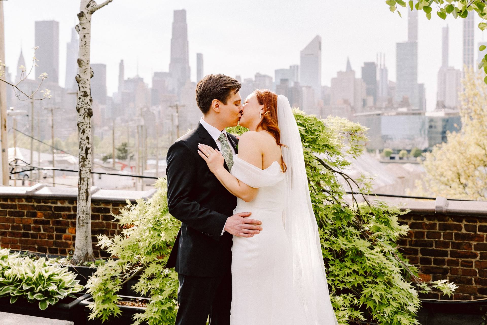 Golden rooftop kiss framed by greenery and the Manhattan skyline
