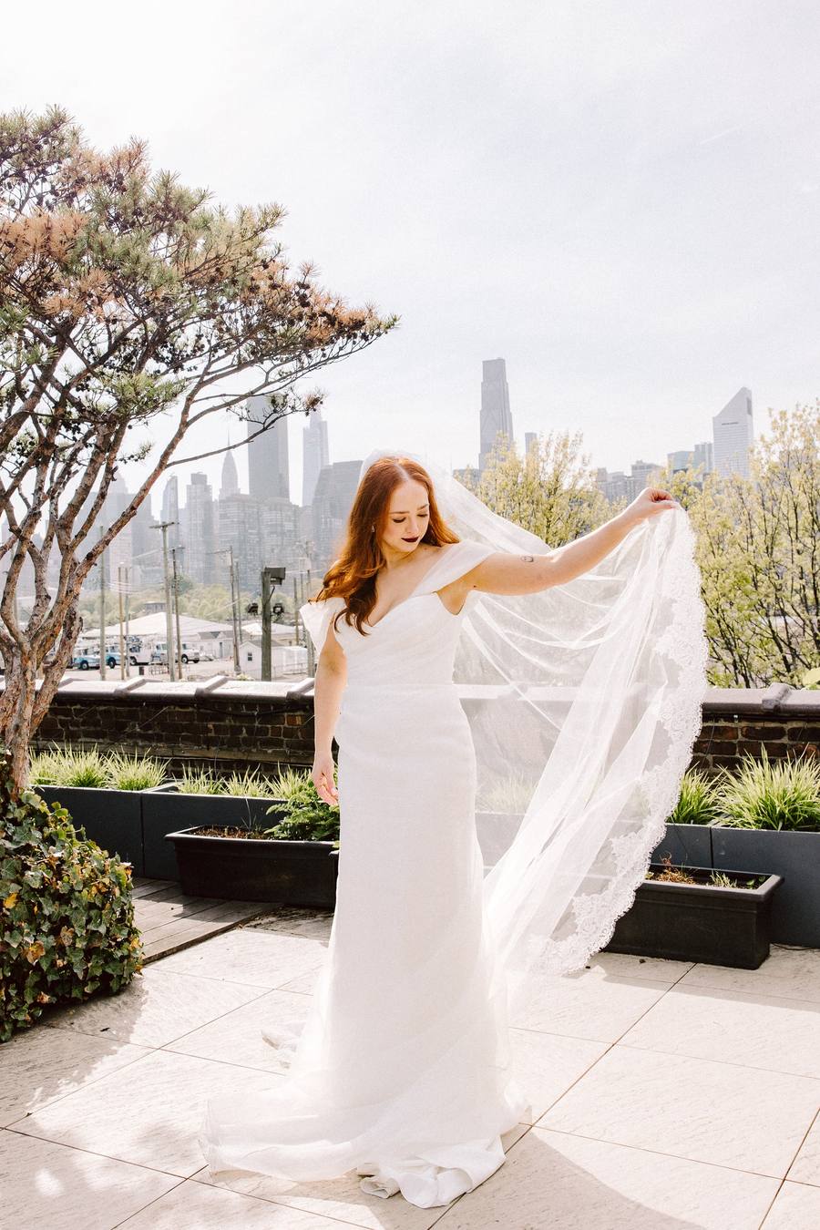 Bride tossing her veil skyward in a rooftop garden