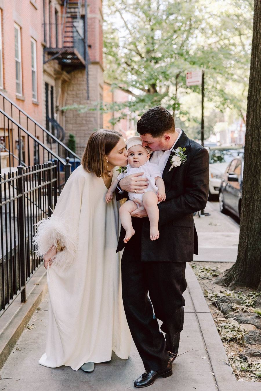 Newlyweds with their baby on a brownstone stoop