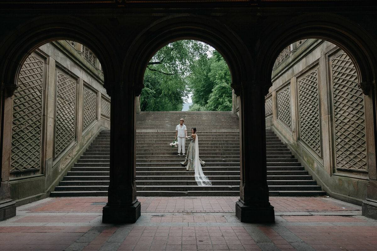 Tiny couple beneath grand park arches