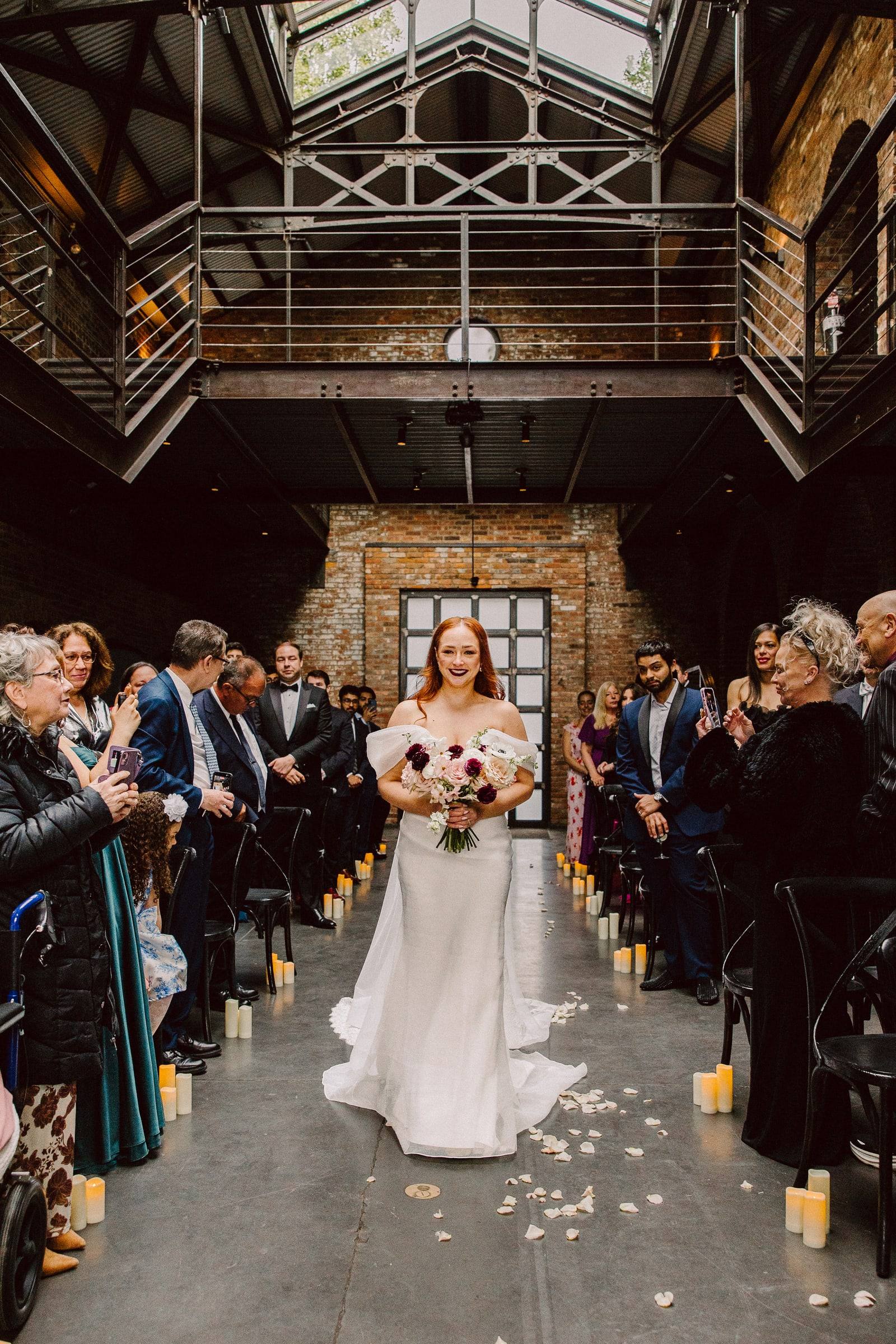 Bride entering the aisle under industrial brick arches
