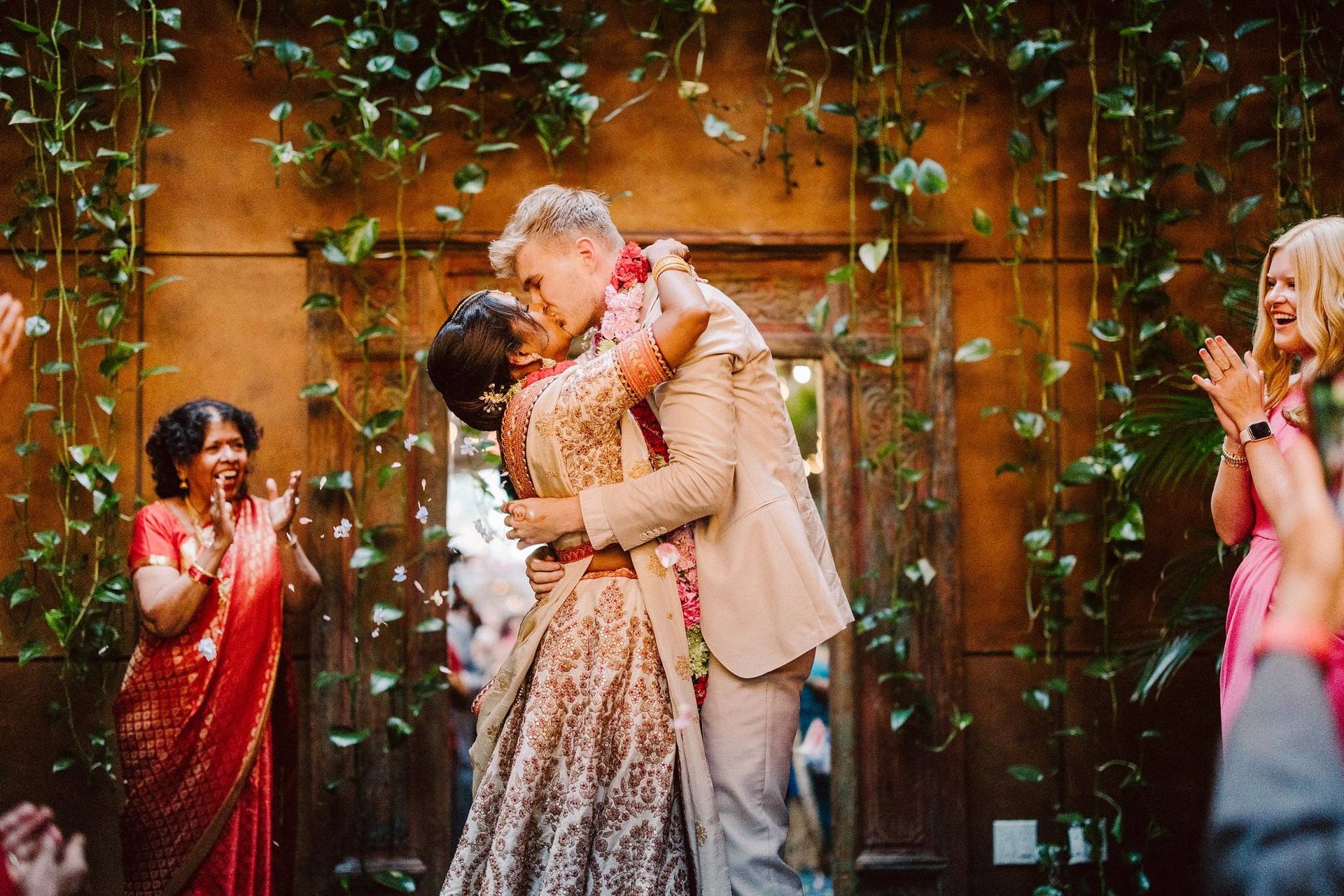 Garland embrace under ivy-covered ceremony arch