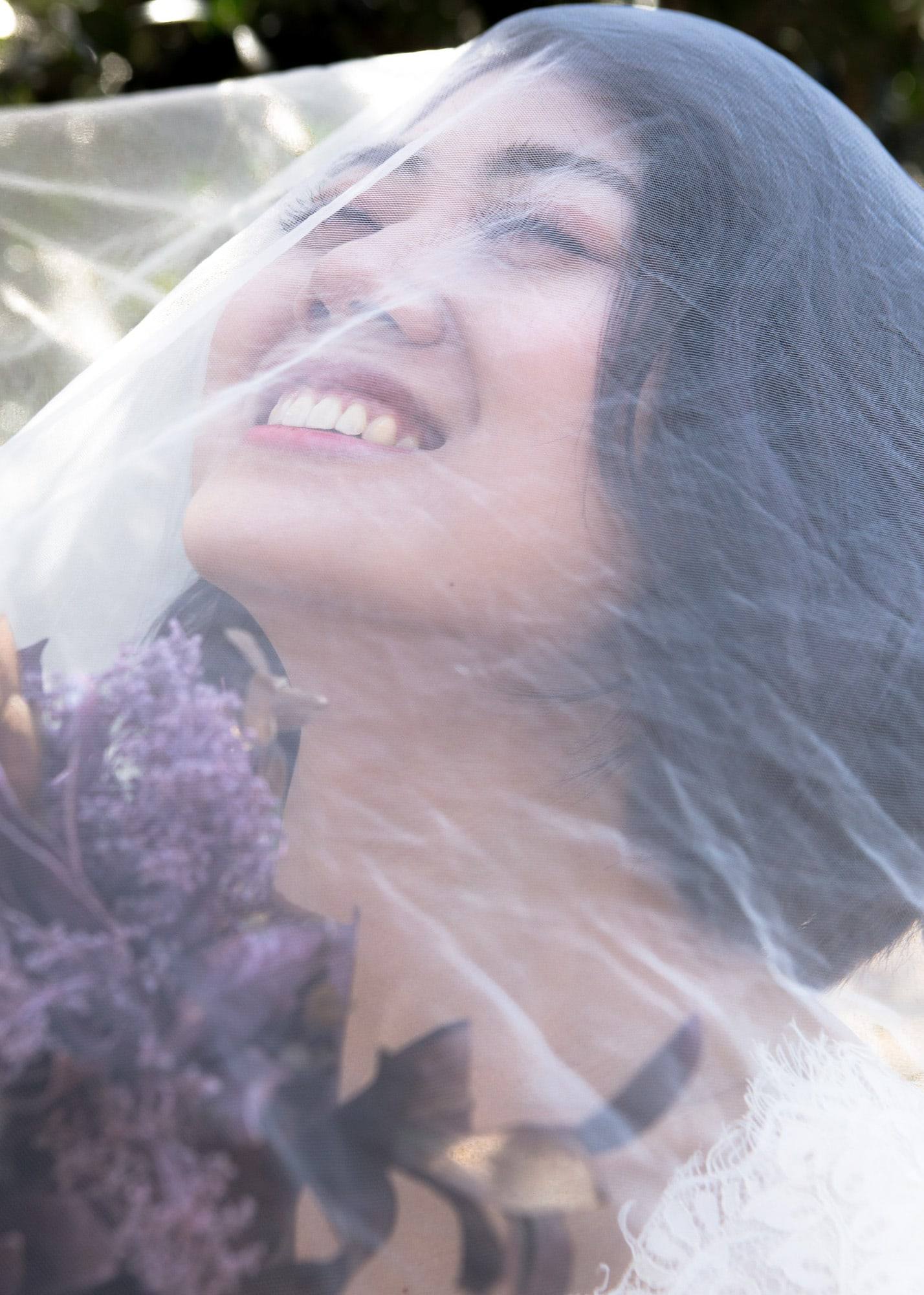 Laughing bride beneath the veil