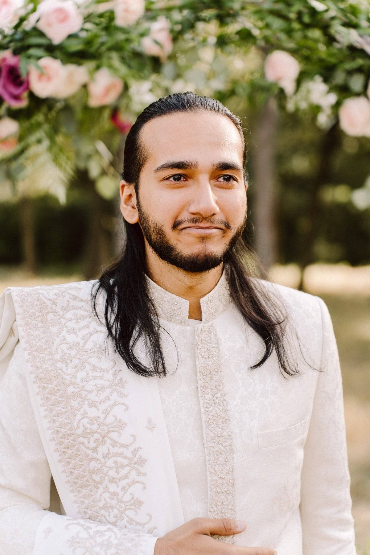 Groom in ivory sherwani among florals