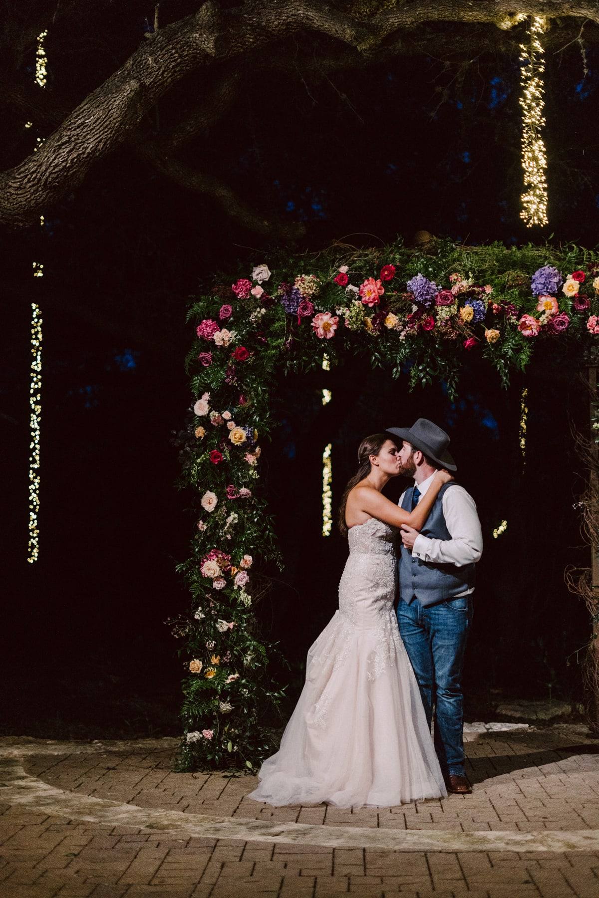 Night kiss beneath a floral arch