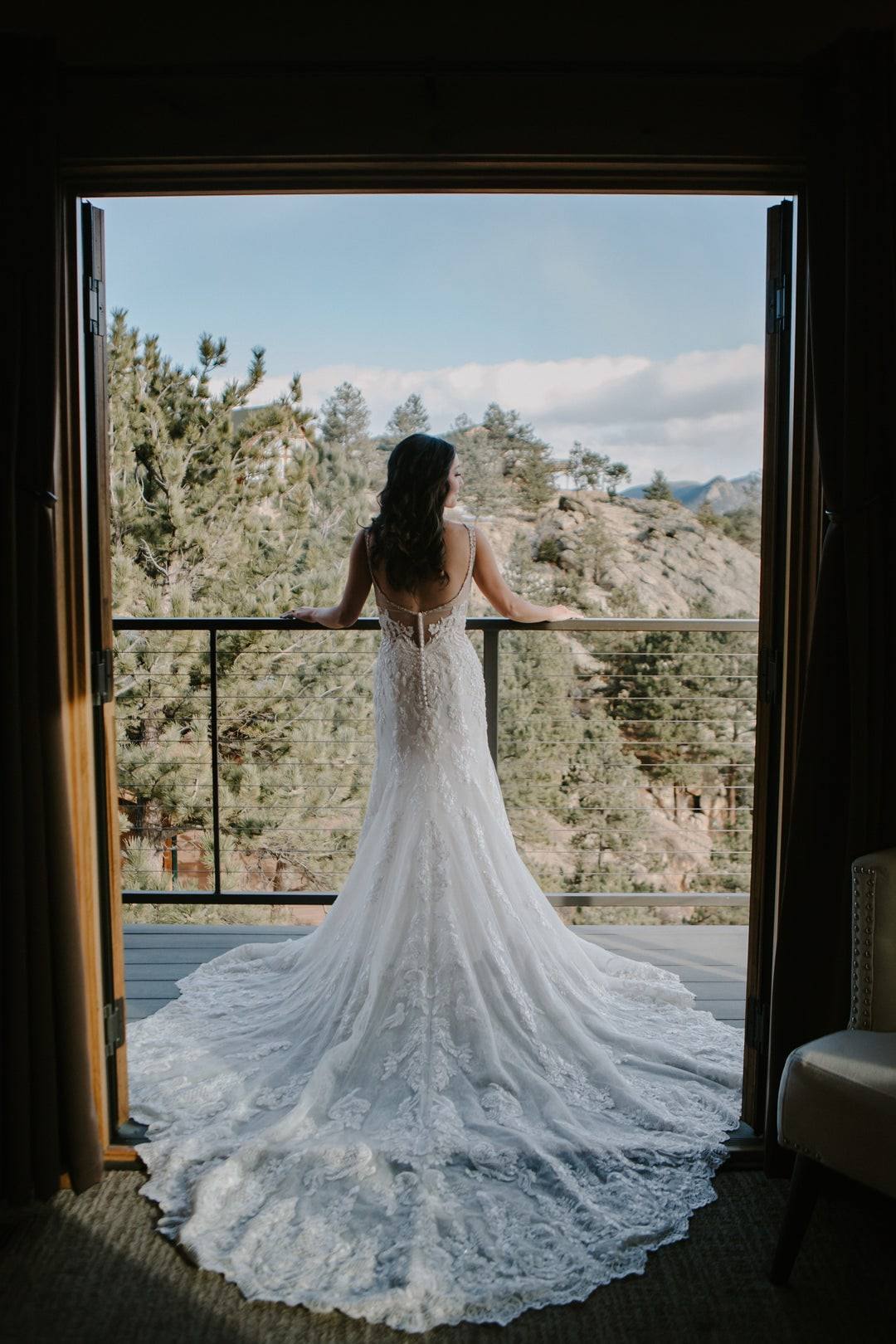 Gown train spilling from a picture window, mountain vista