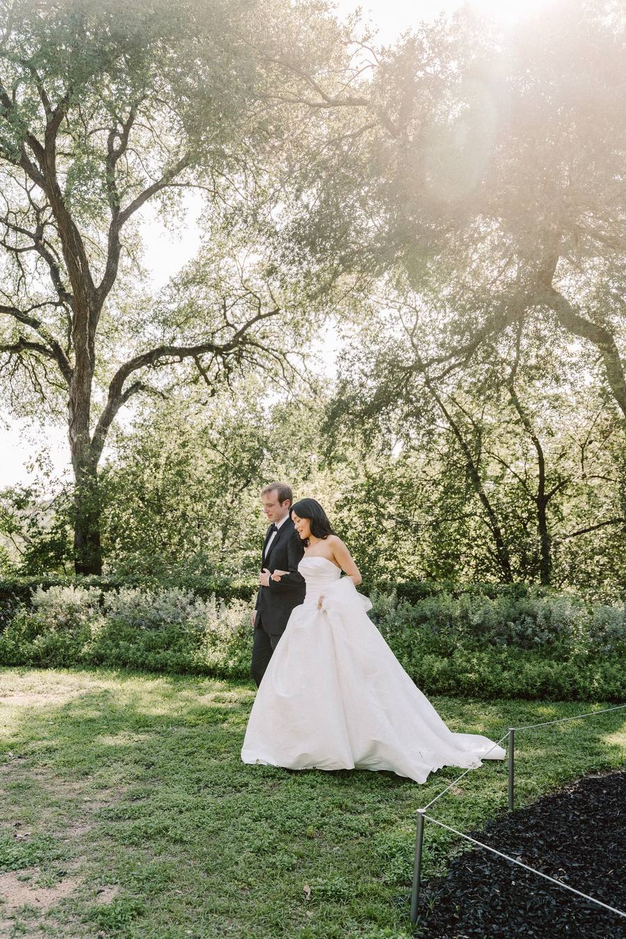 Bride and father crossing a golden garden clearing