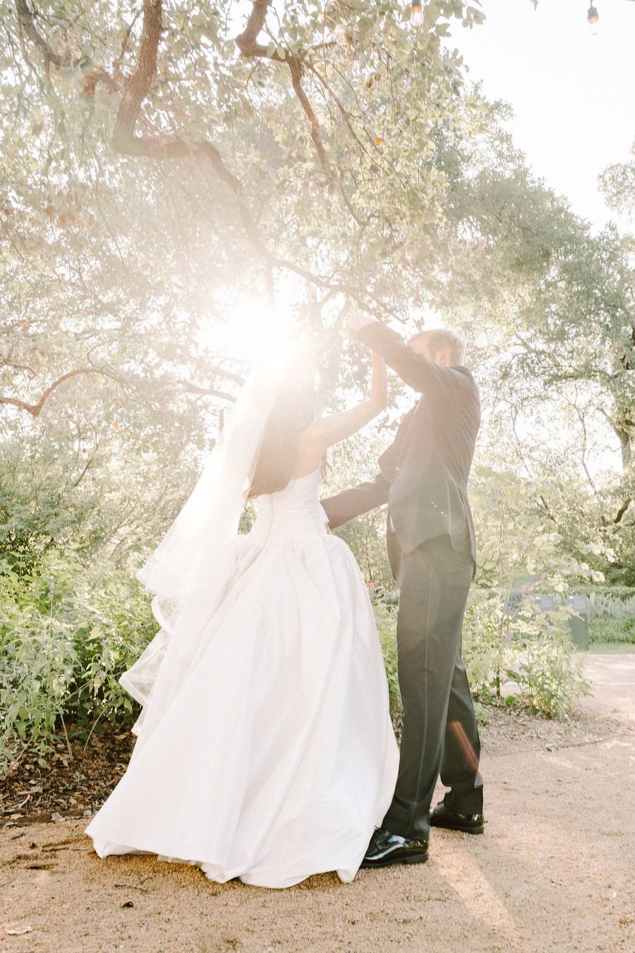 Sunburst through the tree canopy behind a twirling couple