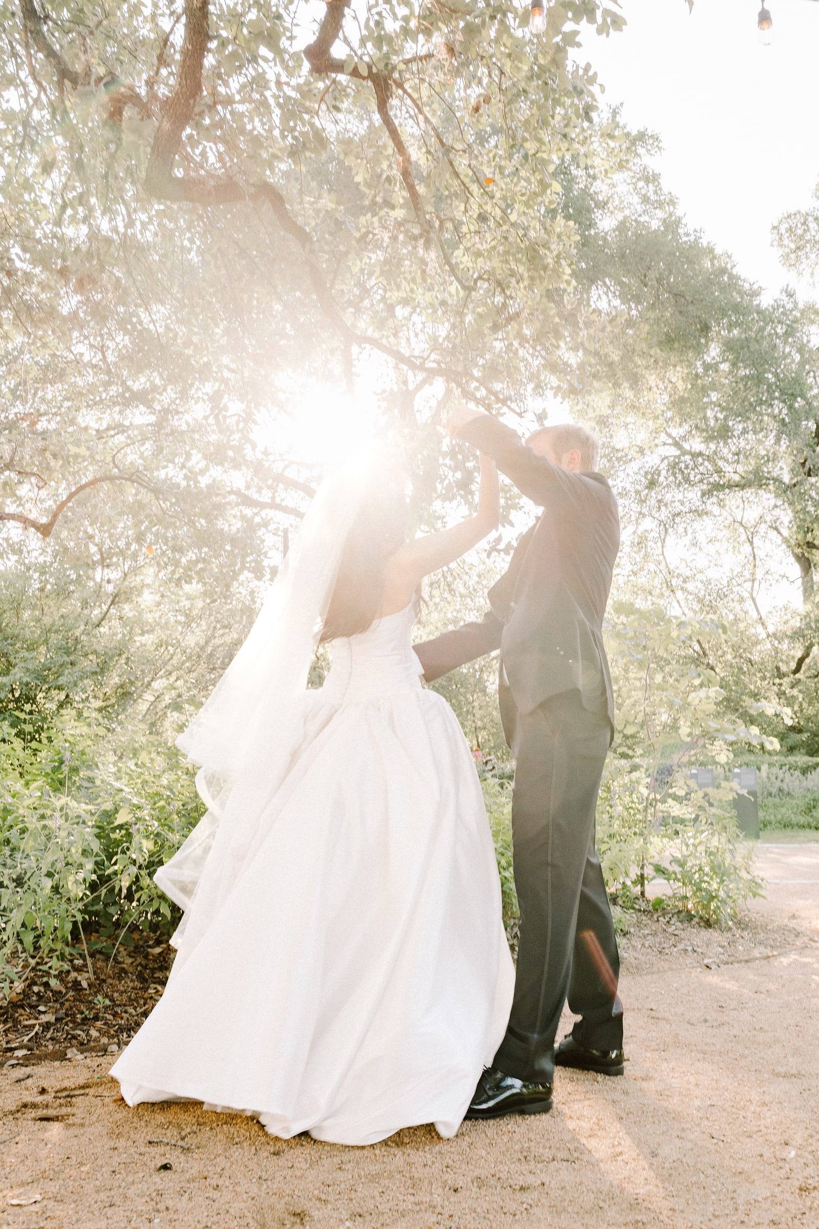 Sunburst through the tree canopy behind a twirling couple