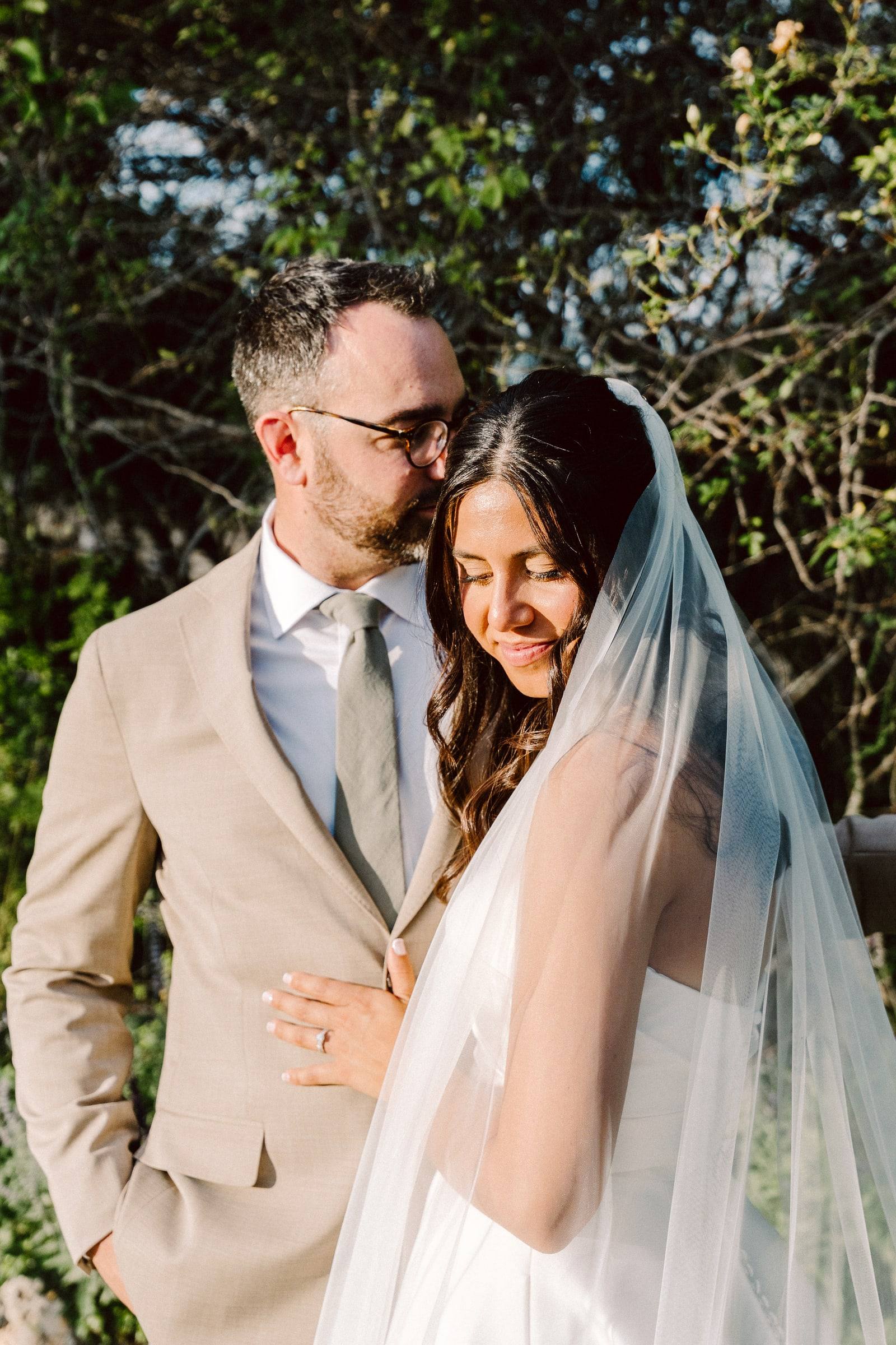 Veil-wrapped couple beneath a tree